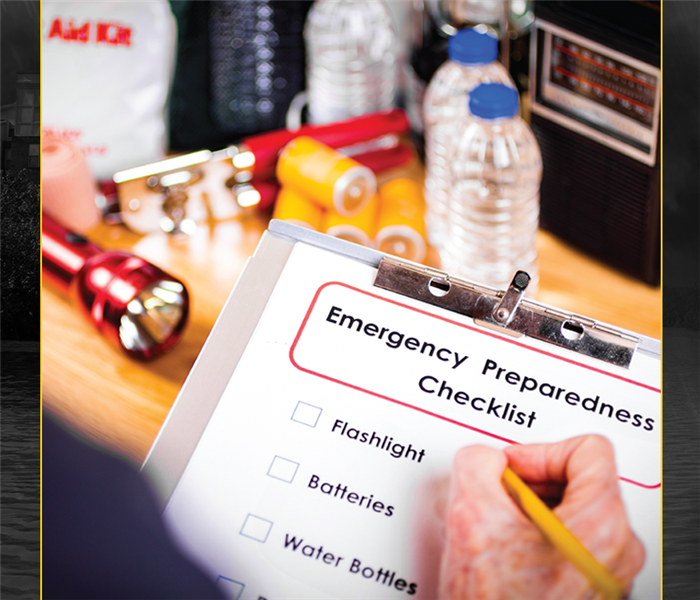 Photo of clipboard with emergency preparedness checklist and hand with pencil checking items off