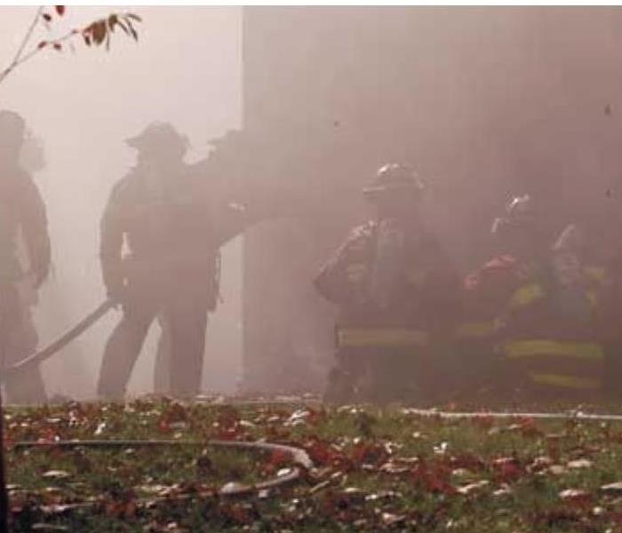 Firefighters surrounded by smoke battling a house fire
